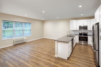 an empty kitchen with an island and stainless steel appliances at The Point at Gateways, New Jersey  